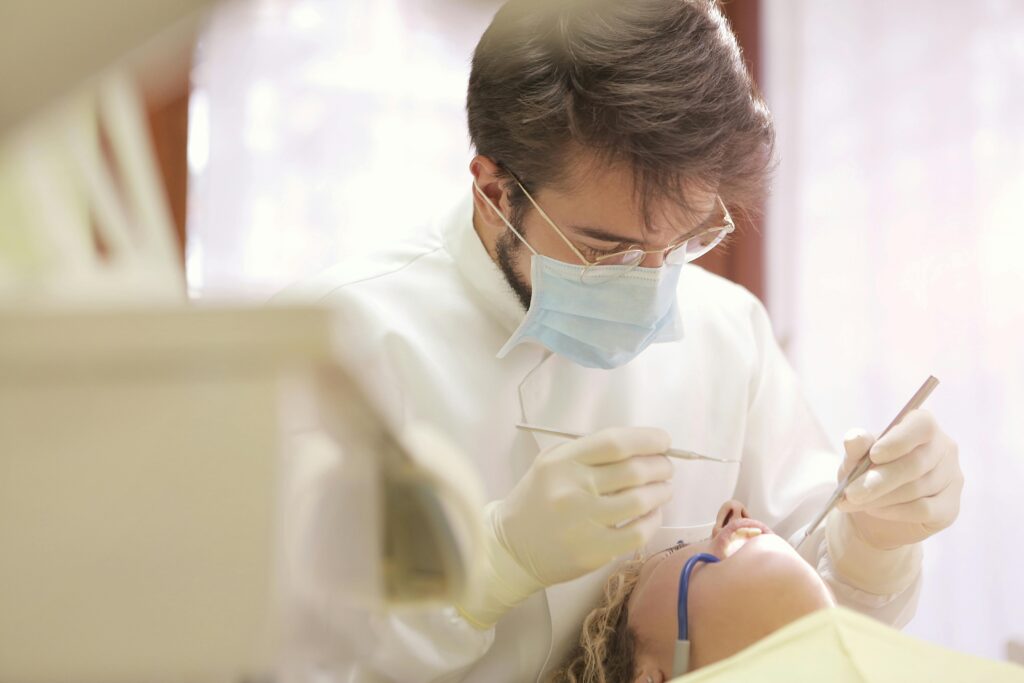 Dentist in face mask conducting a dental examination with tools in clinic setting.